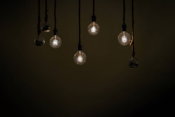 Close up to a group of hanging classic Tungsten Lamp in the dark area with rope. - Foto, Imagen