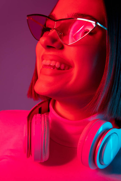 Caucasian womans portrait isolated on pink studio background in multicolored neon light - Foto, Imagem