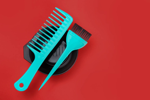 Bowl for hair dye, a brush and comb on a red background - Fotografie, Obrázek
