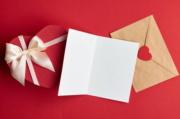 Valentines day card mockup with envelope and heart gift box on red paper background, top view, copy space - Фото, зображення