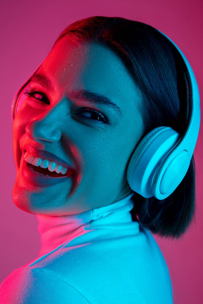 Caucasian womans portrait isolated on pink studio background in multicolored neon light - Photo, Image