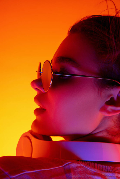 Kaukasische Frauenporträt isoliert auf orangefarbenem Studiohintergrund in buntem Neonlicht - Foto, Bild