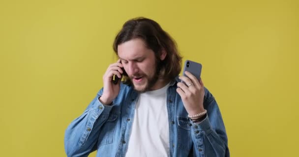 Gefrustreerde man aan het praten op twee mobiele telefoons - Video