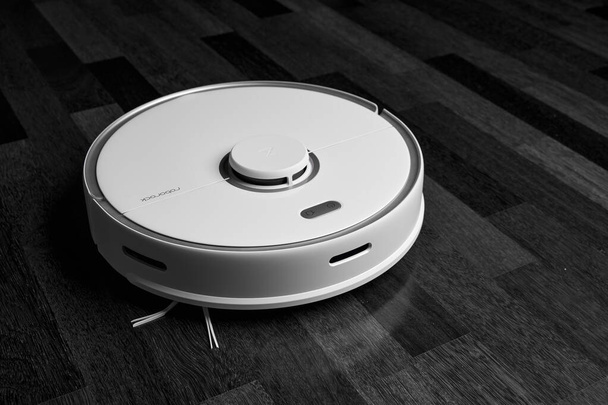 Smart Robot Vacuum Cleaner Xiaomi roborock s5 max on wood floor. Robot vacuum cleaner performs automatic cleaning of the apartment. 04.12.2020, Rostov region, Russia - Photo, Image