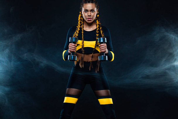 African american woman athlete bodybuilder. Muscular young fitness sports woman workout with dumbbells in fitness gym. - Photo, Image