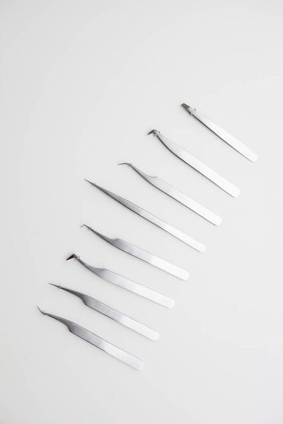 tools for eyelash extension and eyebrow design. cosmetic tweezers in silver color on a white background - Fotografie, Obrázek