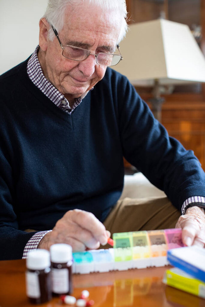 Senior Man At Home Organizing Medication Into Pill Dispenser  - Fotografie, Obrázek