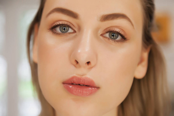 Cute young woman with perfect make-up. Close-up of face of pretty model with natural makeup. Spa and beauty salon, skin care and healthy complexion. Concept of style, satisfaction health. Copy space - Фото, изображение