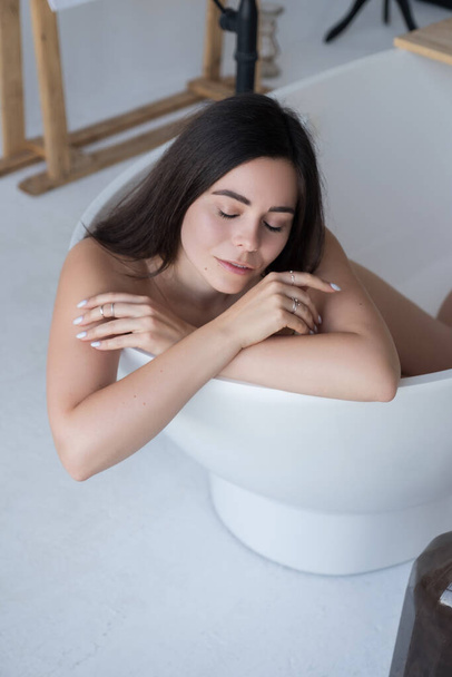 Brunette caucasian adult woman lay in bath relaxing. Sensual sexy portrait at home. - 写真・画像