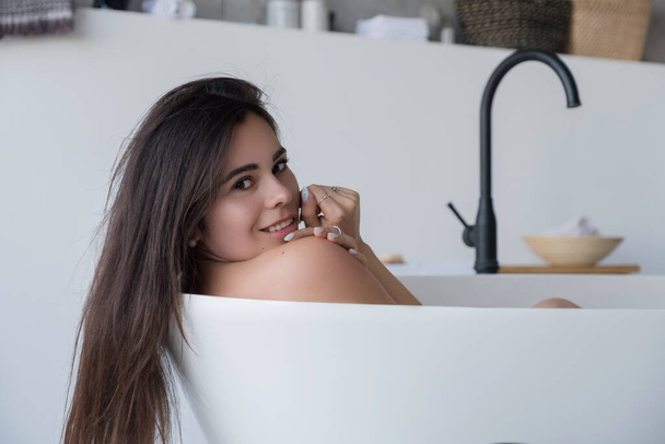 Μπρουνέτ καυκάσια ενήλικη γυναίκα ξαπλωμένη στο μπάνιο χαλαρώνοντας. Αισθησιακό σέξι πορτρέτο στο σπίτι. - Φωτογραφία, εικόνα