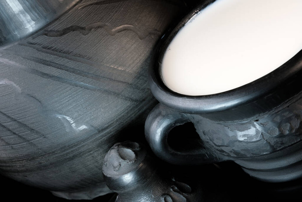 Leite de vaca pasteurizado fresco em uma tigela de barro preto em um fundo preto close-up macrofotografia - Foto, Imagem