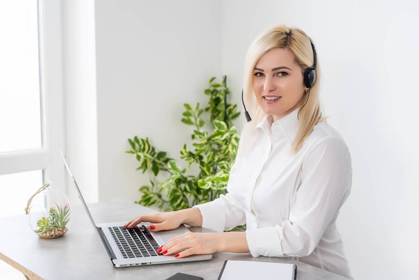 Portret van vrolijke klantenservice vrouwelijke telefoonoperator in headset, tegen witte wand achtergrond. Oproepcentrum voor advies- en assistentiediensten. - Foto, afbeelding