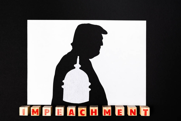17.01.2021, Moscow, Russia. The concept of impeachment. Silhouette of the former president of the USA on a black and white background. Inside the silhouette of the Capitol. Wooden cubes with the word impeachment. Flat lay. - Photo, Image