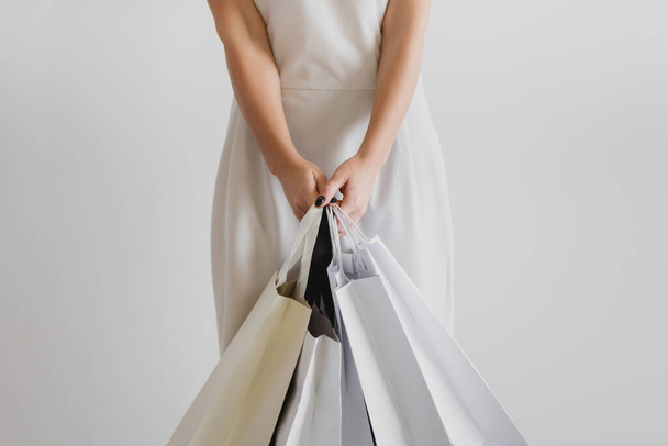 Cropped image of woman holding shopping bags on white background. - Zdjęcie, obraz