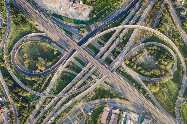 Luftaufnahme eines Verkehrsknotenpunktes oder Autobahnkreuzes mit stark befahrenem Stadtverkehr, der auf der Straße beschleunigt. Knotenpunkt-Transportnetz per Drohne. - Foto, Bild