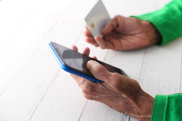 elderly women hand holding credit card and using smart phone shopping online  - Фото, зображення