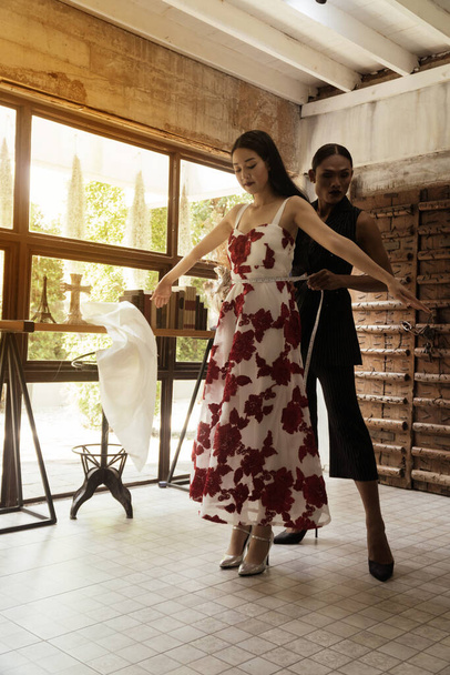 Muotisuunnittelijat mittaavat kauniita aasialaisia nuoria naisia studiossa. - Valokuva, kuva
