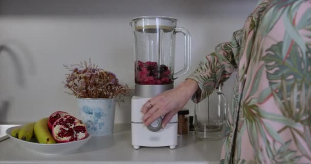 close-up de uma mão feminina ligando suavemente um liquidificador para preparar seu smoothie fresco para o café da manhã - Filmagem, Vídeo