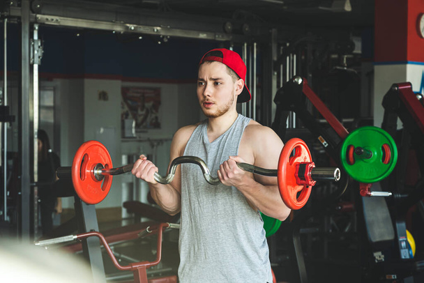 Young active muscular man performs exercises with a barbell in the gym. Power training - Fotó, kép