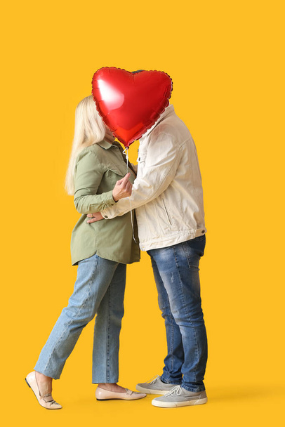 Mature couple with balloon on color background. Valentine's Day celebration - Photo, Image