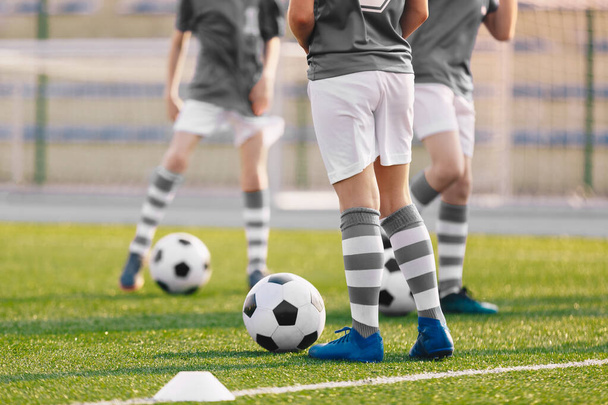 Fiúk a fociedzésen. A játékosok gyakorolják az európai labdarúgást egy nyári napon. Gyerekek sportolnak az iskolai füves stadionban - Fotó, kép