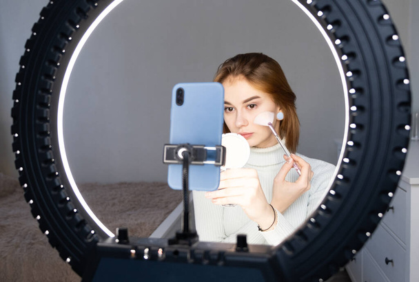 Eine Beauty-Bloggerin moderiert einen Home Stream. Maskenbildner filmt Online-Workouts per Telefon von seinem Schlafzimmer aus. Make-up für sich selbst per Video. - Foto, Bild