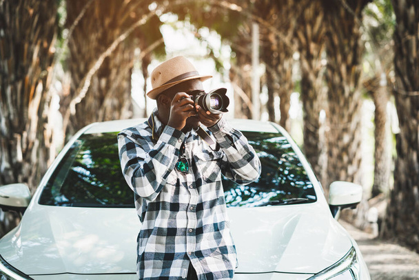 Фотограф африканський мандрівник на дорозі з білою машиною і фотоапаратом
 - Фото, зображення