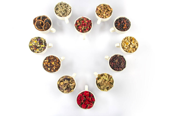Różne rodzaje ziołowych składników herbaty w filiżankach na białym tle. Leki ziołowe naturalne. - Zdjęcie, obraz