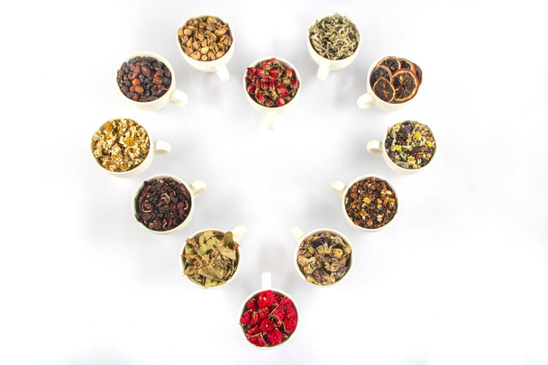 Varios tipos de ingredientes de té de hierbas en tazas sobre fondo blanco. Medicina de hierbas naturales. - Foto, Imagen