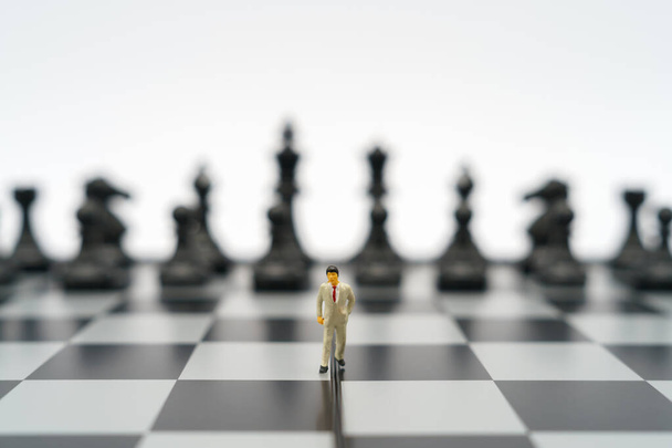 ミニチュアビジネスマン2人のチェス盤の上にチェスの駒を背に立ってビジネスでの交渉。背景ビジネスの概念やコピースペースの戦略的概念として. - 写真・画像