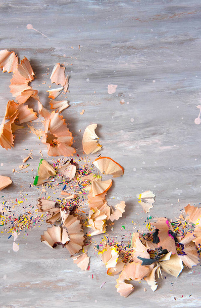 Wooden pencil shavings and colorful crumbs of graphite from sharpener on gray background. Top view. - Photo, Image