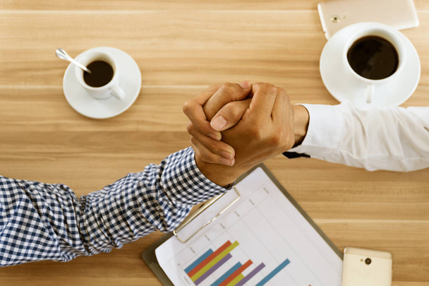 Top view two hand businessman partner ή επιχειρηματικοί αντίπαλοι συγκρούονται χέρι παλεύουν στο τραπέζι στο καφέ. - Φωτογραφία, εικόνα