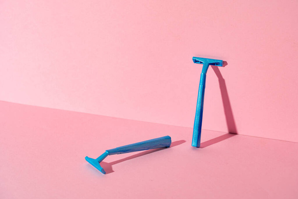 Kék eldobható borotvák rózsaszín papír háttér - Fotó, kép