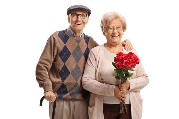 Elderly couple standing with red roses isolated on white background - Zdjęcie, obraz