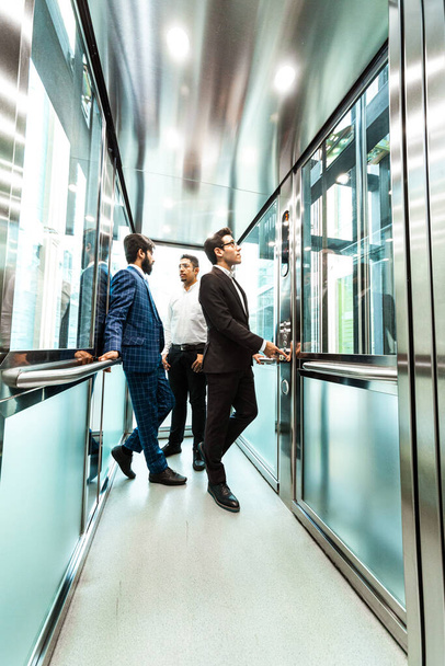 Business team group going on elevator. Business people in a large glass elevator in a modern office. Corporate businessteam and manager in a meeting. - Фото, зображення