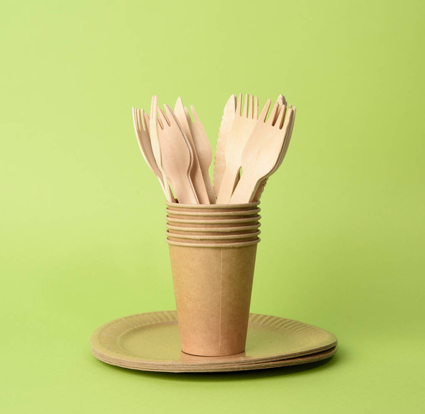 brown paper cup, plates on a green background. Plastic rejection concept, zero waste, close up - Photo, Image
