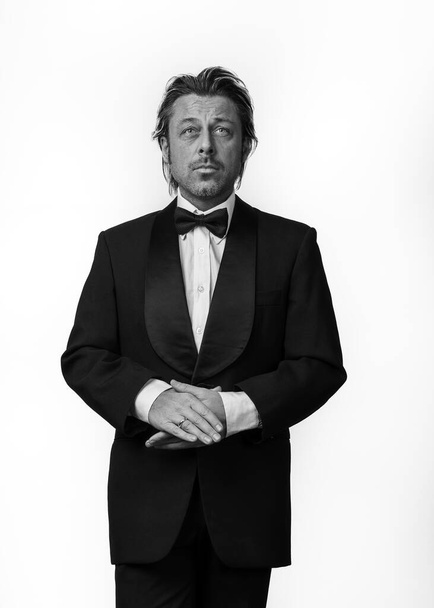 Man in tuxedo in front of white background. Black and white photo. - Photo, image