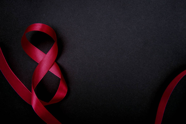 On a black background, a pink satin ribbon in the form of the number eight. Gift wrap. The concept of March 8 and Valentine's Day.A greeting card. - Foto, Bild