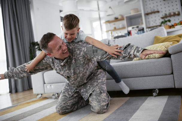 wojskowy człowiek bawi się z synem w domu  - Zdjęcie, obraz