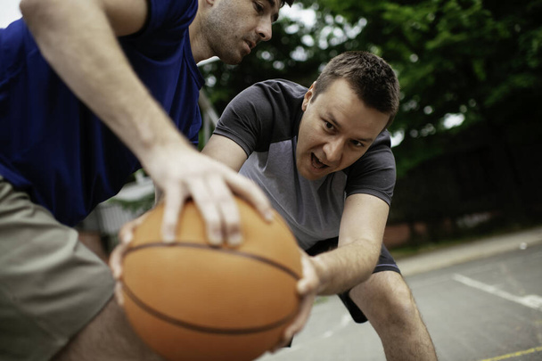 Двоє молодих людей грають у баскетбол у парку. Друзі мають товариський матч на відкритому повітрі
 - Фото, зображення