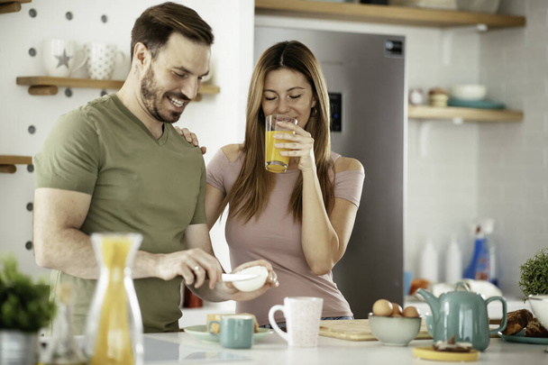 Young couple making sandwiches at home. Loving couple enjoying in the kitchen. - Fotó, kép