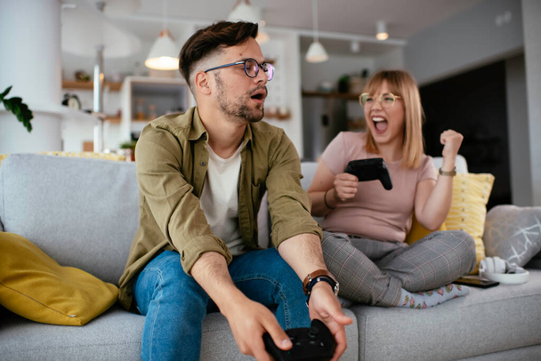 couple playing video game on sofa at home - Photo, image