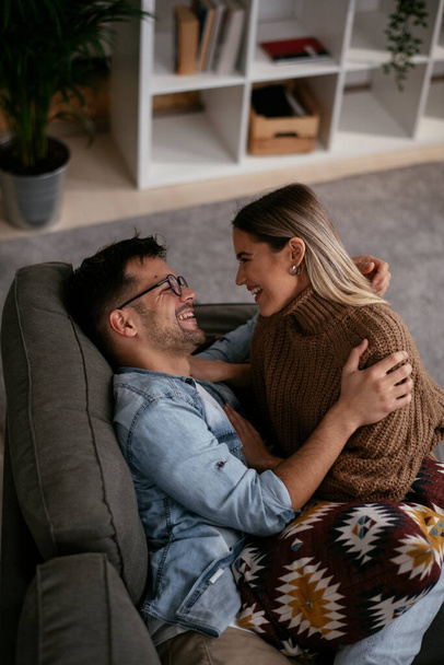 Young loving couple relaxing on sofa together. Happy couple enjoying at home. - Fotoğraf, Görsel