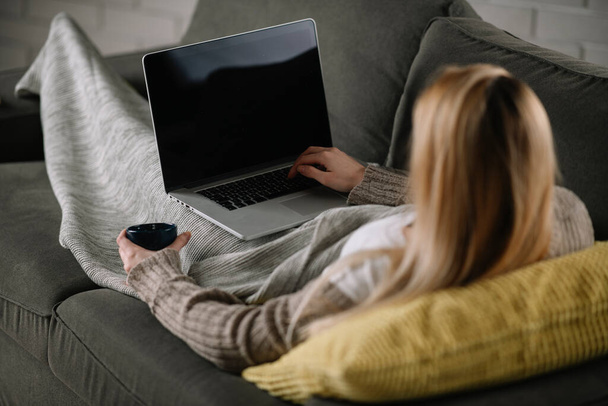 Beautiful blonde woman watching movie on her laptop at home. - Foto, afbeelding