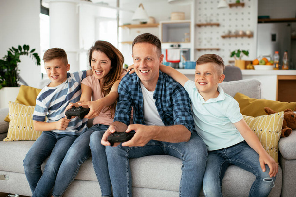  Šťastný milující pár hrají videohry s dětmi doma. - Fotografie, Obrázek