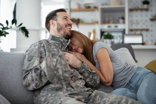 Szczęśliwy żołnierz zaskakuje żonę w domu. młody żołnierz przytula żonę. - Zdjęcie, obraz