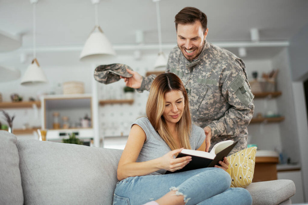 幸せな兵士は自宅で妻を驚かせた。若い兵士の抱擁妻. - 写真・画像