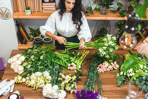 Attractive young woman florist is working in a flower shop. - Fotoğraf, Görsel