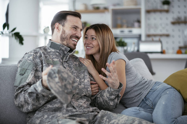 Happy soldier surprise his wife at home. Young soldier hugging wife. - Zdjęcie, obraz