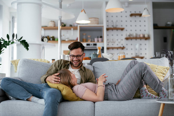 Husband and wife enjoying on sofa. Happy couple relaxing in living room. - Foto, afbeelding